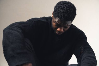 Yenilen Afro-Amerikalı erkekler beyaz arka planda oturuyorlar - orta boy