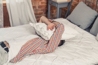 Kafkasyalı yorgun bir adam yatağına uzanmış ve yüzünü beyaz yastıkla örtmüş.