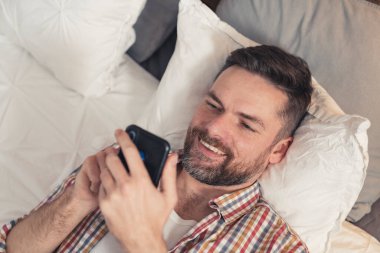 Yakışıklı Avrupalı adam telefonunu kullanıyor ve sosyal medya aracılığıyla arkadaşlarıyla sohbet ediyor.