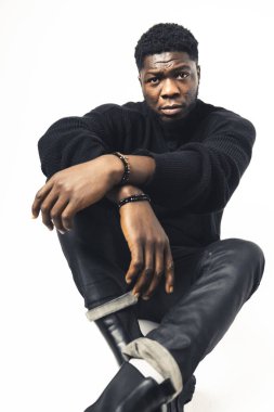 Kameraya yoğun bir şekilde bakan Afroamerikalılar beyaz arka planda oturuyorlar.