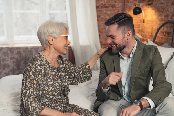 Lyckliga släktingar äldre mor och hennes medelålders affärsman son skämta och skratta — Stockfoto