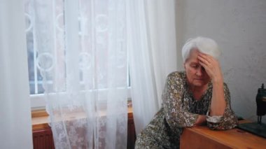 Gri saçlı Kafkas büyükanne, büyükanne ve büyükbaba günü boyunca tek başına oturup kafasına dokunuyor.