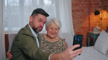 Kafkasyalı akrabalar bir yatakta oturuyor ve aptal suratlar yapıyor ve akıllı telefonla selfie çekiyorlar.