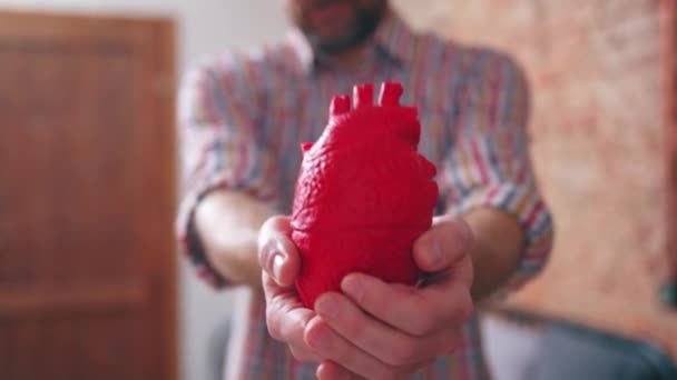 Людина, що тримає штучне серце нагадує про проблеми зі здоров'ям, хвороби та серцево-судинні захворювання — стокове відео
