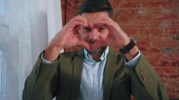 Caucasiano de meia-idade homem em uma jaqueta elegante fazendo forma de coração com as mãos — Vídeo de Stock