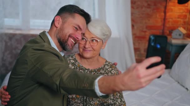 Duizendjarige zoon en zijn oudere moeder het nemen van een selfie met een smartphone viering van Moederdag — Stockvideo