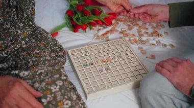 Beyaz, orta yaşlı bir adam anneler gününde yaşlı annesiyle kelime oyunu oynuyor.