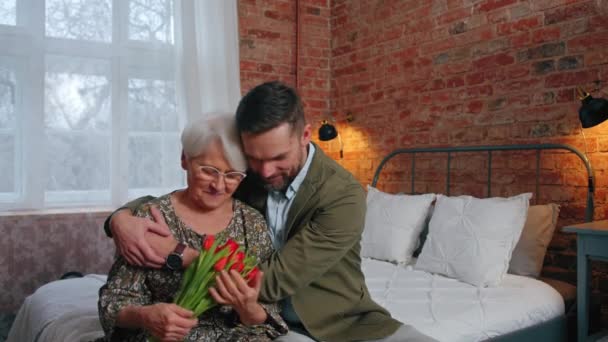 Contenido caucásico abuela en un abrazo con su nieto hombre de negocios de mediana edad celebrando el Día de los Abuelos — Vídeo de stock