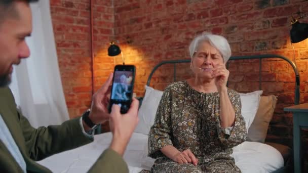 Vigyorgó tartalom idős nyugdíjas anya pózol egy fotó készítette középkorú fia anyák napja — Stock videók