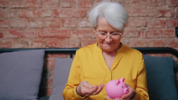 Ικανοποιημένη ηλικιωμένη ηλικιωμένη γιαγιά γυναίκα εξοικονομεί χρήματα στον κουμπαρά του — Αρχείο Βίντεο