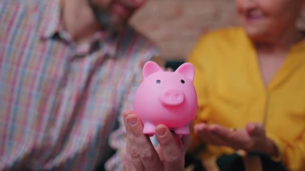 Sorrindo mulher europeia em seus 60 anos brincando com seu filho, investindo e economizando dinheiro usando o mealheiro — Vídeo de Stock