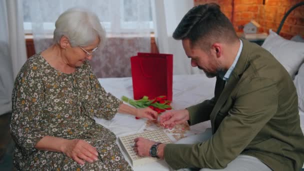 Parenti, nonna e il suo nipote maggiore giocare puzzle vocabolario insieme nella sua camera da letto — Video Stock