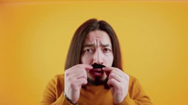 Hareket konsepti. Komik beyaz adam sahte bıyık takıp aptal suratlar yapıyor..