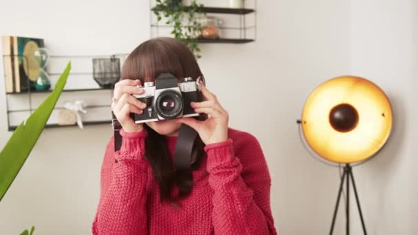 Jovem criadora freelance em seu estúdio. Mulher caucasiana alegre segurando sua câmera durante a sessão fotográfica. — Vídeo de Stock