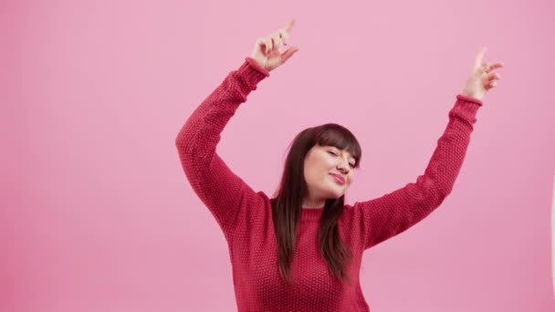 Full av energi positiva kaukasiska brunett kasta händerna i luften och ler över rosa bakgrund. Studioinspelning. — Stockvideo