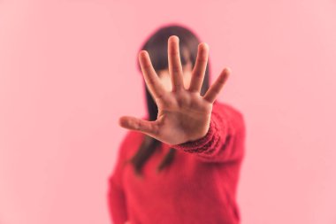 Dur işareti, avuç içi, el kamerada, sembol. Ön plana odaklan. Pembe arkaplanlı stüdyo çekimi.