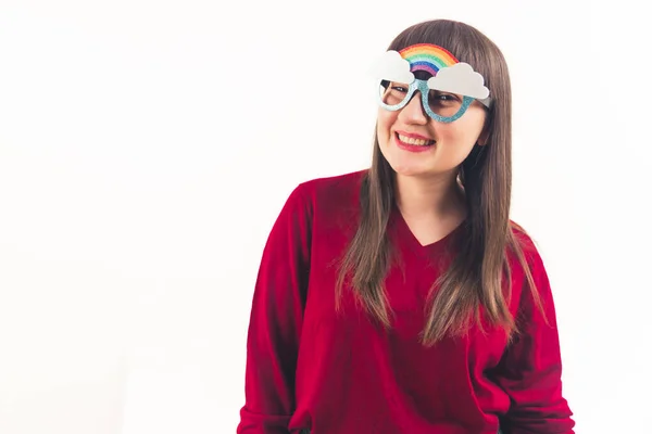 笑容可亲的年轻欧洲女人戴着可笑的彩虹眼镜，对着相机微笑。中演播室拍摄白色背景. — 图库照片