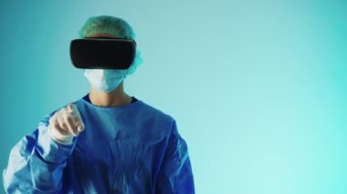 Gözlüklü ve koruyucu üniformalı bir doktor parmaklarıyla havaya dokunuyor. Modern teknoloji kavramı.