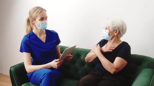 Blanke vrouwelijke arts heeft een huisbezoek aan haar bejaarde grijs-harige patiënt. — Stockvideo