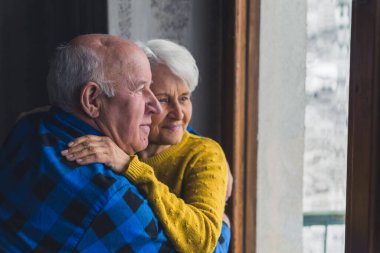 Yaşlı ve yaşlı bir çift kışın pencerenin kenarında kucaklaşıp sarılıyorlar. Küçük yaşta aşk ve birliktelik. 