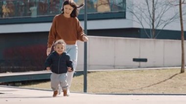 Kahkahalar atan kıvırcık saçlı Afro-Amerikan çocuk. Annesinin önünde koşuyor. 