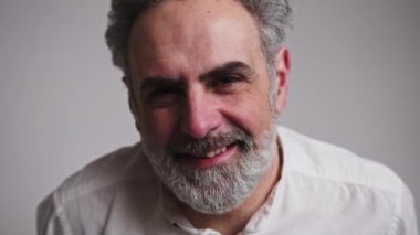 Kameraya gülümseyen beyaz saçlı şık bir adam. Moda stüdyosu ışıklandırması.