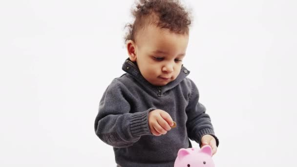 Милий маленький хлопчик кладе монету в рожевий скарбничку і плескає руками - концепція заощаджень — стокове відео