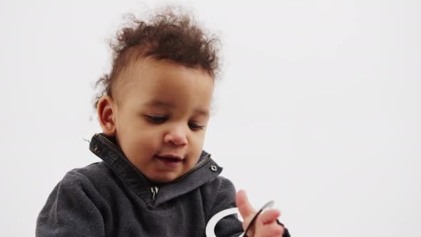 Beautiful curled little boy holding a black mask of moustache and glasses looking into the camera — Stock Video