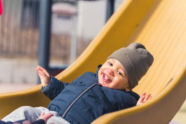 春天的乐趣。可爱的笑着的小男孩在操场上滑行，享受着外面的闲暇时光. — 图库照片