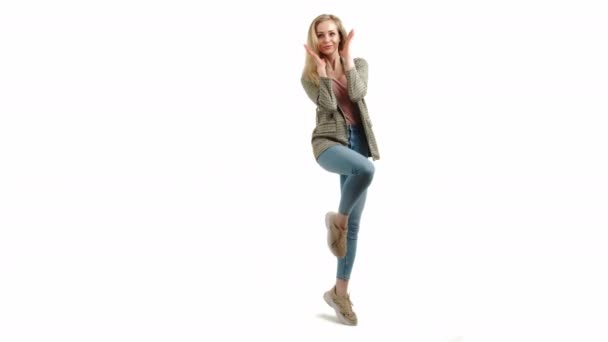 Zaskoczony piękny europejski blondynka dziewczyna z jedną stopą w górę trzymając ręce wyciągnięte i uśmiechając się do kamery full shot studio strzał biały tło — Wideo stockowe