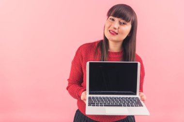 Orta boylu, çekici, beyaz bir kadın elinde açık bir laptop tutuyor. Siyah bir ekran, fotokopi stüdyosu görüntüsü izole edilmiş. 