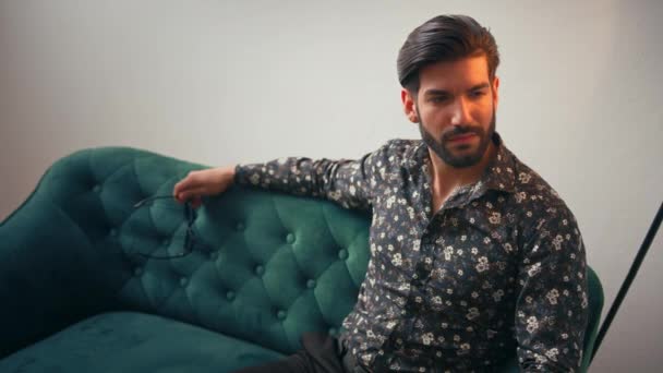 Stylish Elegant Latin American handsome man sitting on the sofa indoors studio shot — стоковое видео