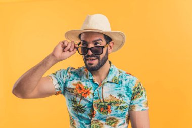 Plaj kıyafetleri içinde genç sakallı Latin Amerikalı adam yan görünüşlü turuncu arka plan medyum yakın çekim tatil konsepti