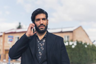 Genç Latin adam telefonda konuşurken düşünüyor.