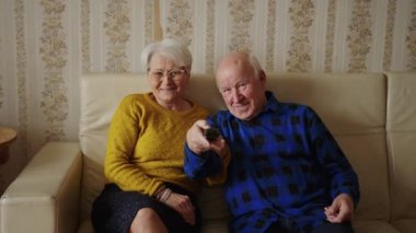 Mutlu yaşlı çift birlikte gülüyor ve televizyon seyrediyor, yavaş.