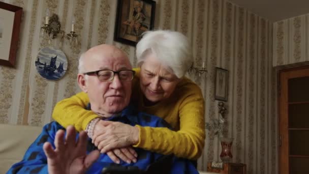 Улыбающиеся пожилые люди Кавказа используют мобильные телефоны и разговаривают, обнимаясь — стоковое видео