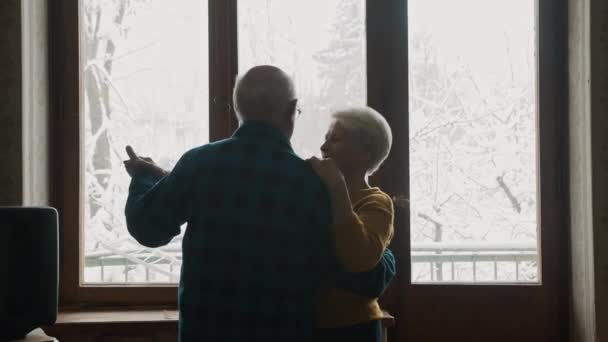 Elderly Caucasion couple dancing and smiling togetherin front of the window — Vídeos de Stock