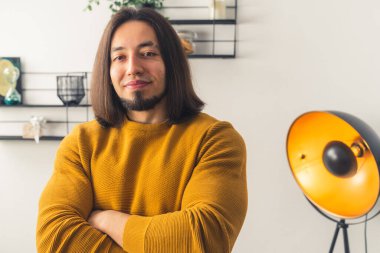 Genç, beyaz bir adam kollarını kavuşturup kameraya bakıyor, özgüvenli bir şekilde arka plan fotokopisini çekiyor. 