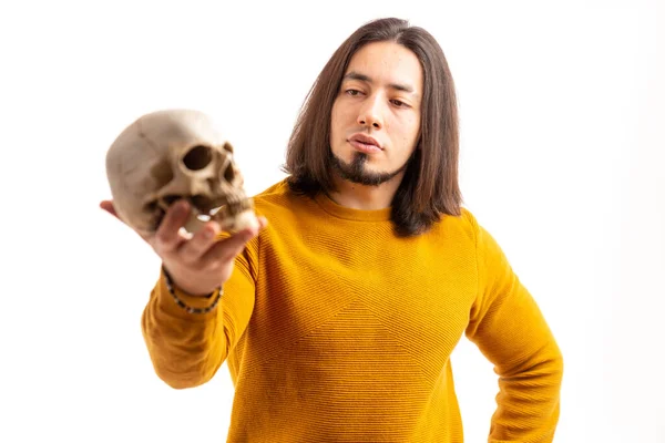 Young Caucasian bearded man holds skull and looks at it white background studio shot isolated — Stockfoto