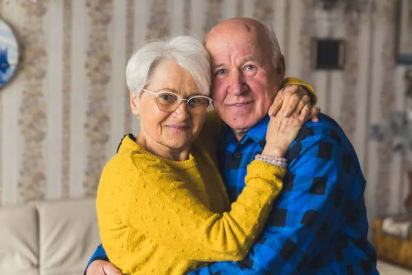 Embrace between caucasian retired grandmother and grandfather. Happy retirement concept. Indoor medium shot. — Stockfoto