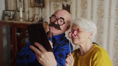 Üst düzey Kafkas çifti komik gözlükler takıp oturma odasında selfie çekiyorlar.