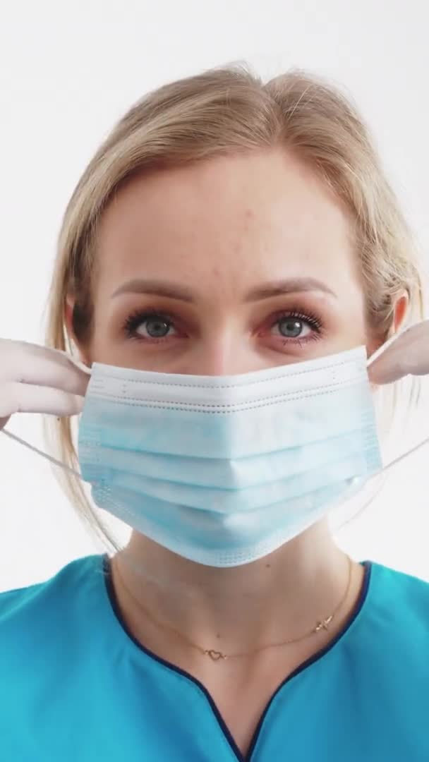 Vertikal video av den attraktiva kvinnan i 20-årsåldern sätta på medicinsk mask för skydd mot infektioner — Stockvideo