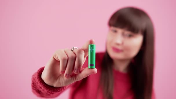 Νεαρή γυναίκα που κρατά τις μπαταρίες απομονωμένες σε ροζ φόντο δείχνοντας προς τα εμπρός — Αρχείο Βίντεο