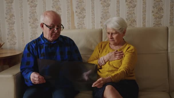 Vecchio uomo anziano che mostra i suoi risultati radiografici a sua moglie a casa — Video Stock