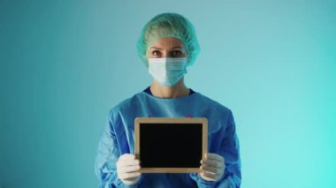 Doktor elinde boş bir karatahta ortamı tutuyordu. Mavi gradyan arka plan stüdyosu tıbbi konsept çekti.