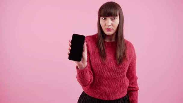 Gros plan portrait attrayant doux belle adolescente gaie tenant un smartphone isolé sur fond rose — Video