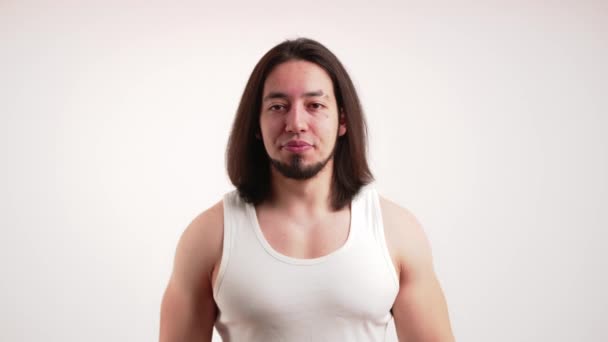 Isolated copy space of a young bearded muscular caucasian man in a tank top plugging his ears because of a sudden noise. White background studio shot. — Video