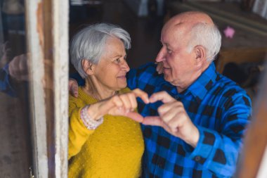 Mutlu yaşlı çift kavramı. Emeklilikte birlikte. Kafkasyalı yaşlı çift parmaklarıyla kameraya kalp işareti gösteriyor..