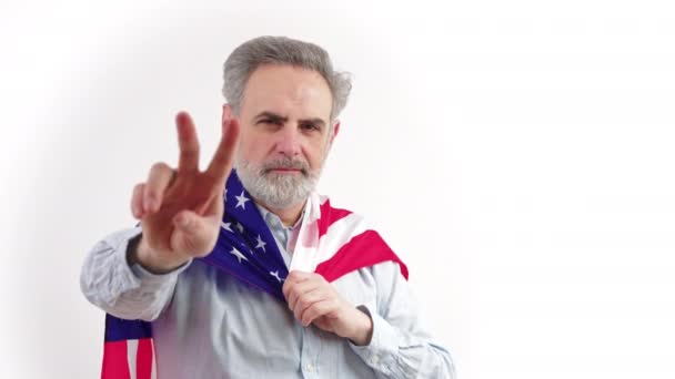 Senior pohledný vousatý muž s americkou vlajkou ukazující gesto kameře, izolovaný, bílý bakalářský — Stock video