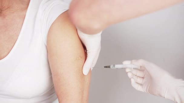 Een prik van een naald in de arm van een blanke patiënt. Vaccin-concept. — Stockvideo